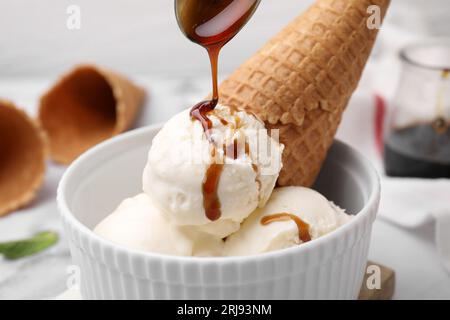 Pouring caramel sauce onto ice cream on table, closeup Stock Photo