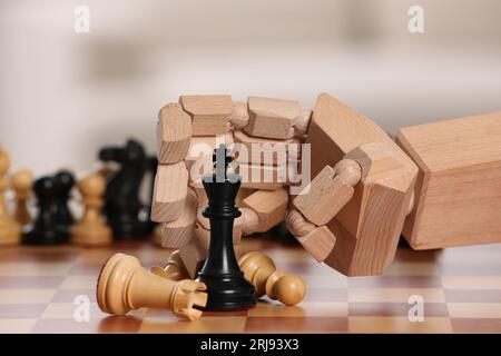 Robot playing chess, closeup. Wooden hand representing artificial intelligence Stock Photo