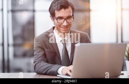 Smiling business man working on laptop at office. Stock Photo