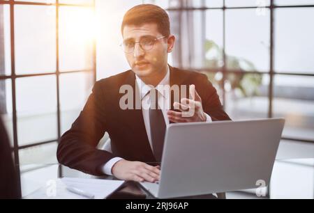 financial consultant in a black suit advises a client sitting at a table Stock Photo