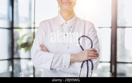 Confident female doctor posing in her office and smiling at camera, health care and prevention concept Stock Photo