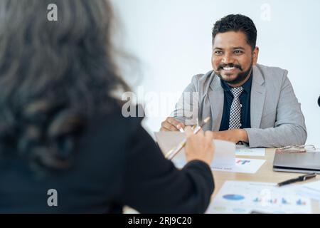 Smiling mature middle aged businessman discussing investing with supervisor businesswoman at meeting room Stock Photo