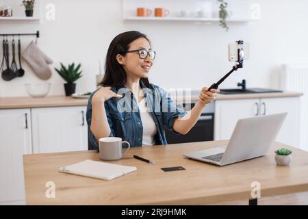Female taking photo via smartphone held by selfie stick Stock Photo