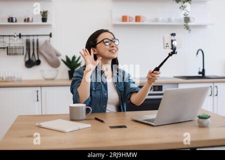 Female taking photo via smartphone held by selfie stick Stock Photo