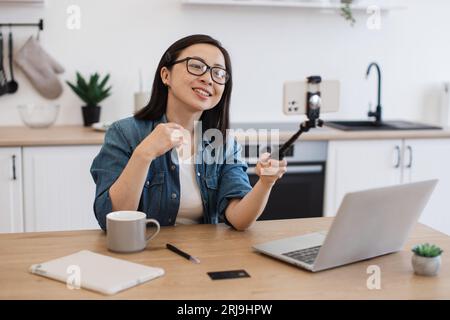 Female taking photo via smartphone held by selfie stick Stock Photo
