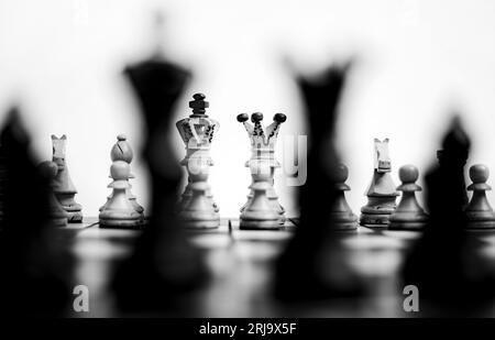 A grayscale shot of a chessboard with a full set of chess pieces arranged on the board. Stock Photo