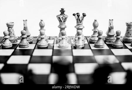 A grayscale shot of a chessboard with a full set of chess pieces arranged on the board. Stock Photo