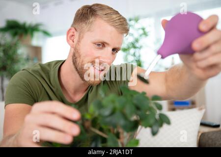 young gardener watering bonsai using sprinkler Stock Photo