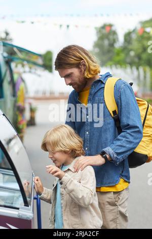 Vertical side view portrait of father and son buying ice cream at festival  and looking in freezer display Stock Photo - Alamy