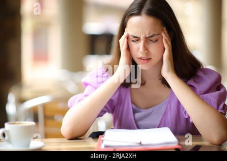 Student studying and suffering migraine in a bar terrace Stock Photo