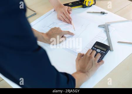 Close up of civil male engineer asian working on blueprint architectural project at construction site at desk in office Stock Photo