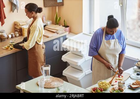 High angle portrait of two African American young women cooking together in cafe kitchen Stock Photo