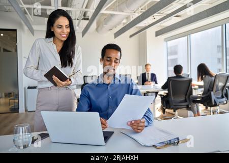 Diverse colleagues using laptop discussing business project working in office. Stock Photo