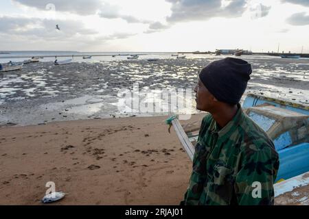 DJIBOUTI , Obock, from here ethiopian migrants try to cross bab el mandeb, red sea, gulf of aden by smuggler boats to Yemen to continue the journey to Saudi Arabia or Europe, ethiopian migrant looking to the sea / DSCHIBUTI, Obock, Meerenge Bab el Mandeb, mit Hilfe von Schleppern versuchen aethiopische Migranten hier über das Rote Meer nach Jemen ueberzusetzen, um weiter nach Saudi Arabien oder Europa zu gelangen Stock Photo