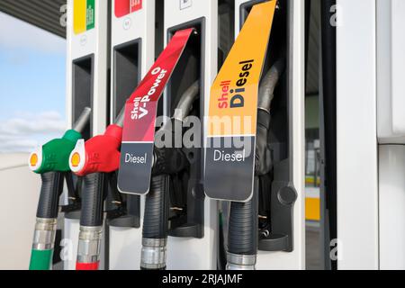 Shell gas pump nozzles at a service station. Close up fuel nozzles for various types of petrol and diesel at a gas station. Stock Photo