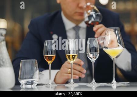 Beginner wine waiter sniffs alcoholic drink during blind tasting. Sommelier school, international certification. Stock Photo