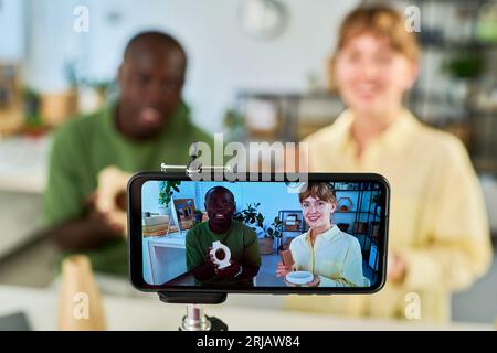 Smartphone screen with two young intercultural bloggers advertising goods they ordered in online shops and describing them to subscribers Stock Photo