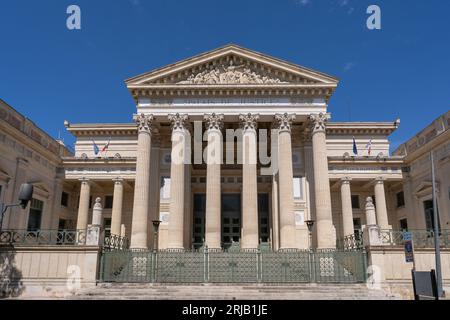 Nîmes, Gard, France - 08 17 2023 : Landscape view of the classical stone facade with columns and pediment representing Justice of historic courthouse Stock Photo