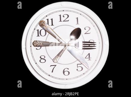 Clock made of knife, spoon and fork on black background. Stock Photo