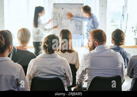 Business and entrepreneurship symposium. Speakers giving talk at business meeting. Rear view of unrecognized participant in audience. Stock Photo