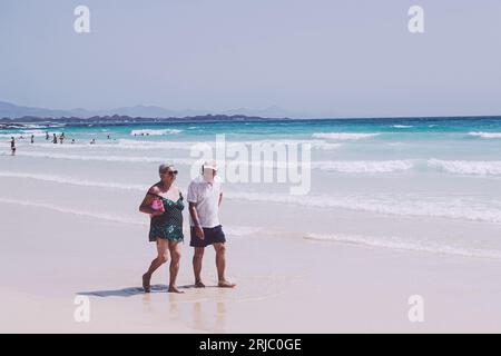 elderly couple walking along a sandy beach.  in love and maybe on holiday as part of their retirement Stock Photo