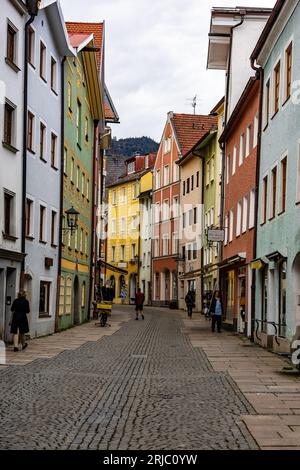 An urban street scene featuring a cobblestone road lined with vibrant, multi-colored buildings. Stock Photo