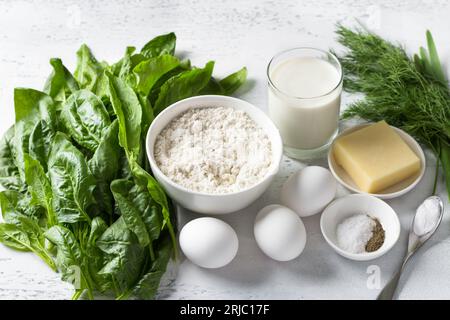 Ingredients: spinach, sorrel, flour, eggs, yogurt, cheese, spices, baking powder and greens for cooking a delicious vegetarian pie or cupcake on a lig Stock Photo