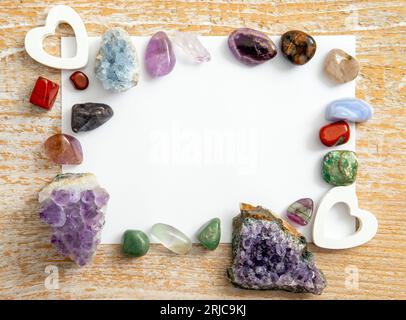Frame made with colorful crystal gemstones with white empty paper page inside. Spiritual esoteric background. Stock Photo