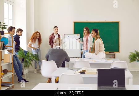 Students discussing study project with lecturer. Girl presenting project during class lesson Stock Photo