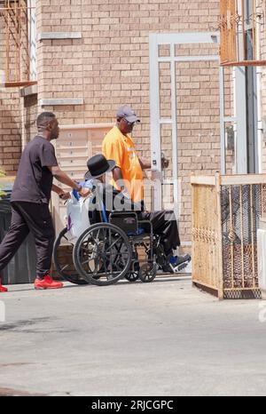 A hasidic man in a wheelchair gets an assist from two aid. In Williamsburg, Brooklyn, New York. Stock Photo