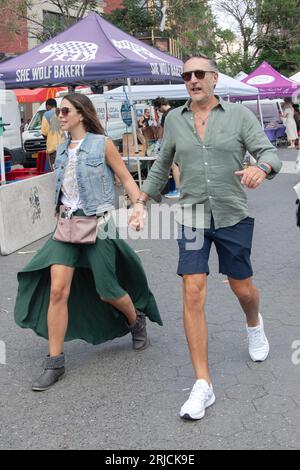An attractive couple walk through the Union Square Green Market, he in shorts, she in a flowing revealing skirt & each with sunglasses. Stock Photo