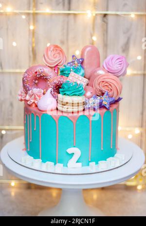 birthday cake with turquoise frosting and pink birthday decorations ready for a birthday party festive background pink donuts lollipops and cupcake 2rjcn1f