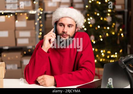 Happy Santa pick up phone purchase order stock detail customer online data delivery at warehouse. Startup small business concept. Christmas sale Stock Photo