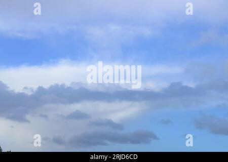 A cloudy winter sky backdrop. White and grey clouds on a mid blue sky. Stock Photo