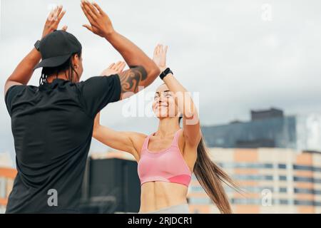 Young athletes giving each other high five after workout on the roof Stock Photo