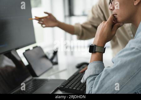 Two developer programmer discussing to checking code on monitor about programming to developing web. Stock Photo