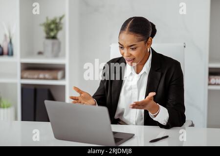 Working stress. Angry black businesswoman having problems with laptop computer, worried ceo sitting at desk in office Stock Photo