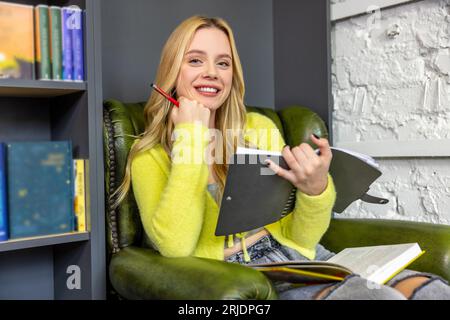 Pretty young woman making notes in library Stock Photo