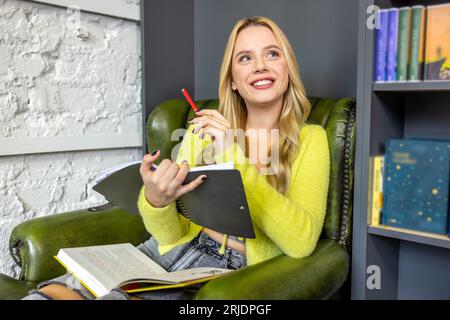 Pretty young woman making notes in library Stock Photo