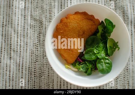 Rissois de Camarao portuguese deep fried pastry pie with shrimps served with greens in white bowl on beige printed textile tablecloth. Food photograhy Stock Photo