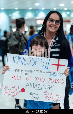 Girl waiting at London Heathrow Airport T3 arrivals hall hoping to greet the Women's England football team arriving from Australia after World Cup Stock Photo
