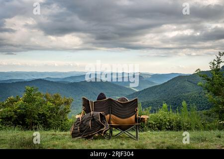 Couple sitting overlooking the Blue Ridge Mountains, Looking Glass Rock near Brevard, North Carolina Stock Photo