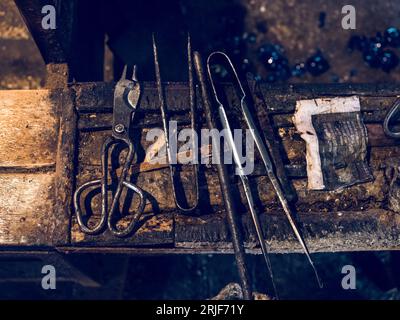 Top view composition of different metal tools for glassblowing placed on shabby wooden surface in workshop Stock Photo