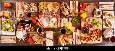 Top view of few charcuterie boards with various snacks with vegetables and bread served with drinks and cutlery in light kitchen Stock Photo
