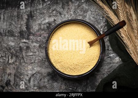 Raw couscous in a black ceramic bowl on a rustic black background table top view Stock Photo