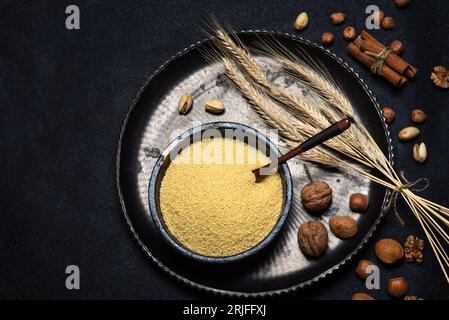 Raw couscous in a black ceramic bowl on a rustic black background table top view Stock Photo