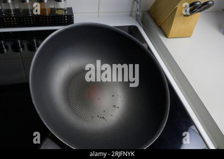 Chips in the Teflon coating on an old frying pan. The bottom of the pan is chipped and cracked. Stock Photo