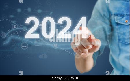 Businesswoman pointing at figure 2024 among others ones on grey background Stock Photo
