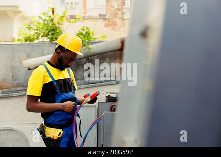 Experienced professional doing annual external air conditioner maintenance, getting equipment ready before starting work. Capable specialist using pressure measurement device to check freon levels Stock Photo