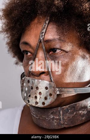 Face portrait of black woman with iron mask of slavery covering her mouth. Studio reproduction. Stock Photo